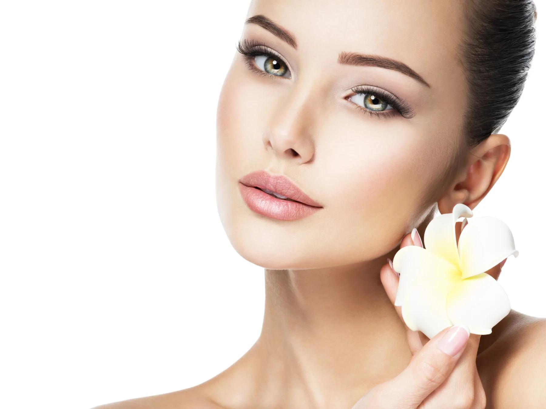 Gesicht mit gepflegten Brauen und einer Frangipani-Blüte